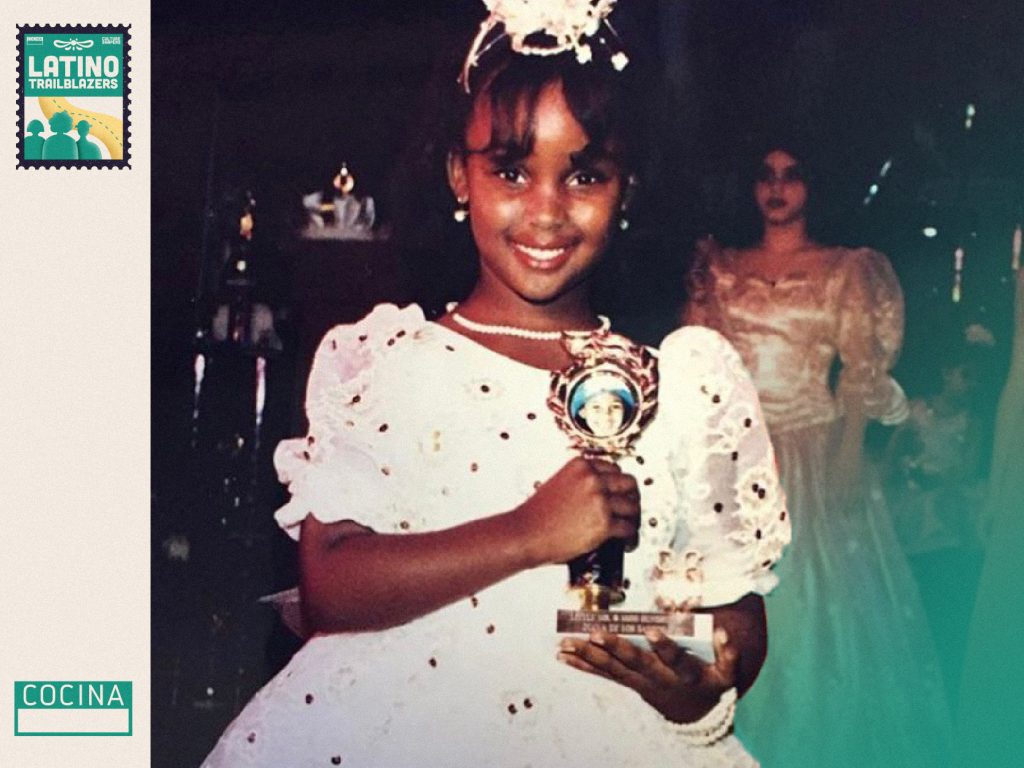 Amara La Negra, part of Latino Trailblazers,  at 8 years old, holding a tropy and smiling to the camera.